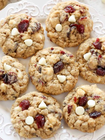 Overhead view of seven oatmeal cranberry cookies on a white plate.